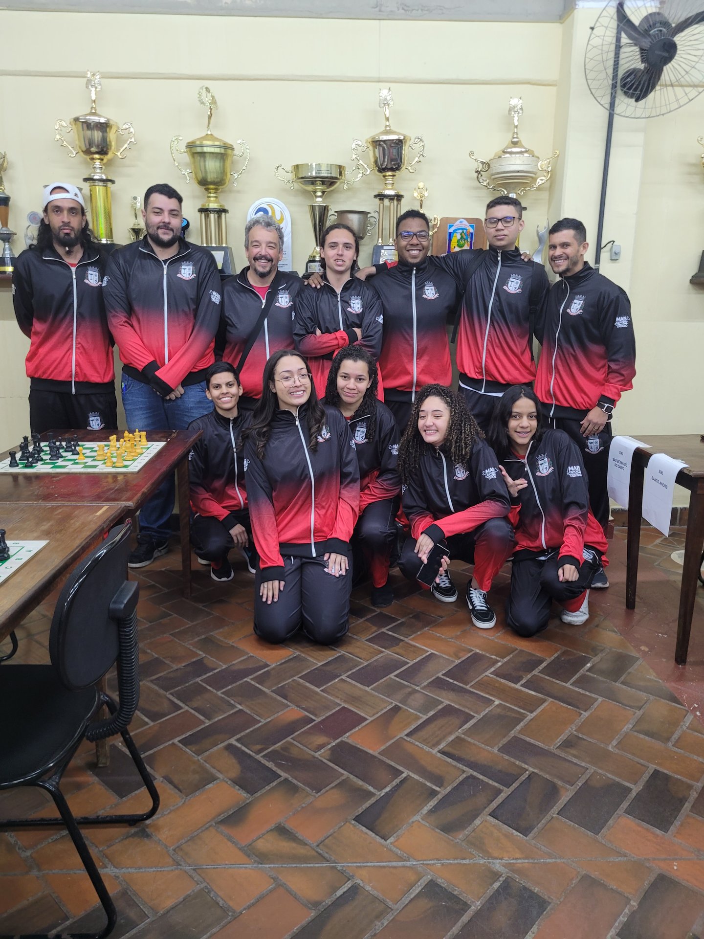 Atletas e comissão técnica ao lado dos troféus conquistados pelo Xadrez Taboão